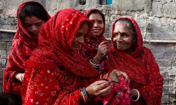 Women light incense while holding roses and a coconut to perform ritual on the occasion of Raksha Bandhan festival at the Shri Laxmi Narayan temple in Karachi,